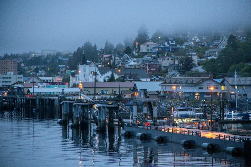 Aerial view of the Ketchikan waterfront and Tongass Highway at dusk, showing the linear city layout between mountains and sea